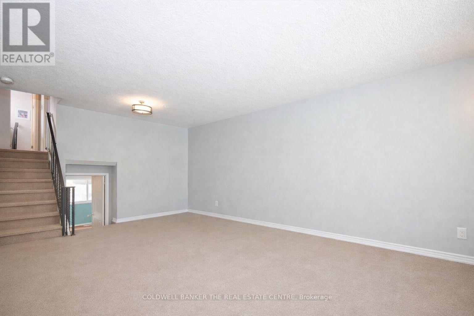 A spacious room with a staircase leading to another room.