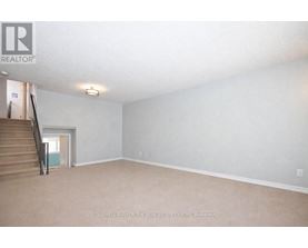 A spacious room with a staircase leading to another room.