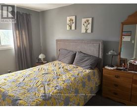 A bedroom with a bed, nightstand, and lamp.