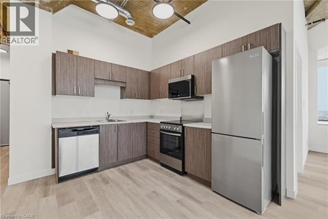 A kitchen with a refrigerator, oven, and microwave.