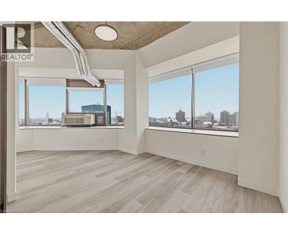 A spacious room with a view of the cityscape through large windows.