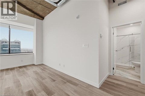 A room with a window overlooking a building with the logo REALTOR on the top left.