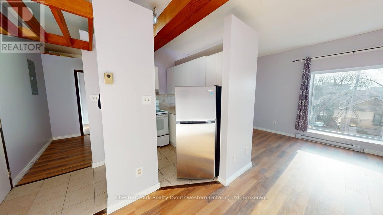 A kitchen with a refrigerator, sink, and wooden floors.