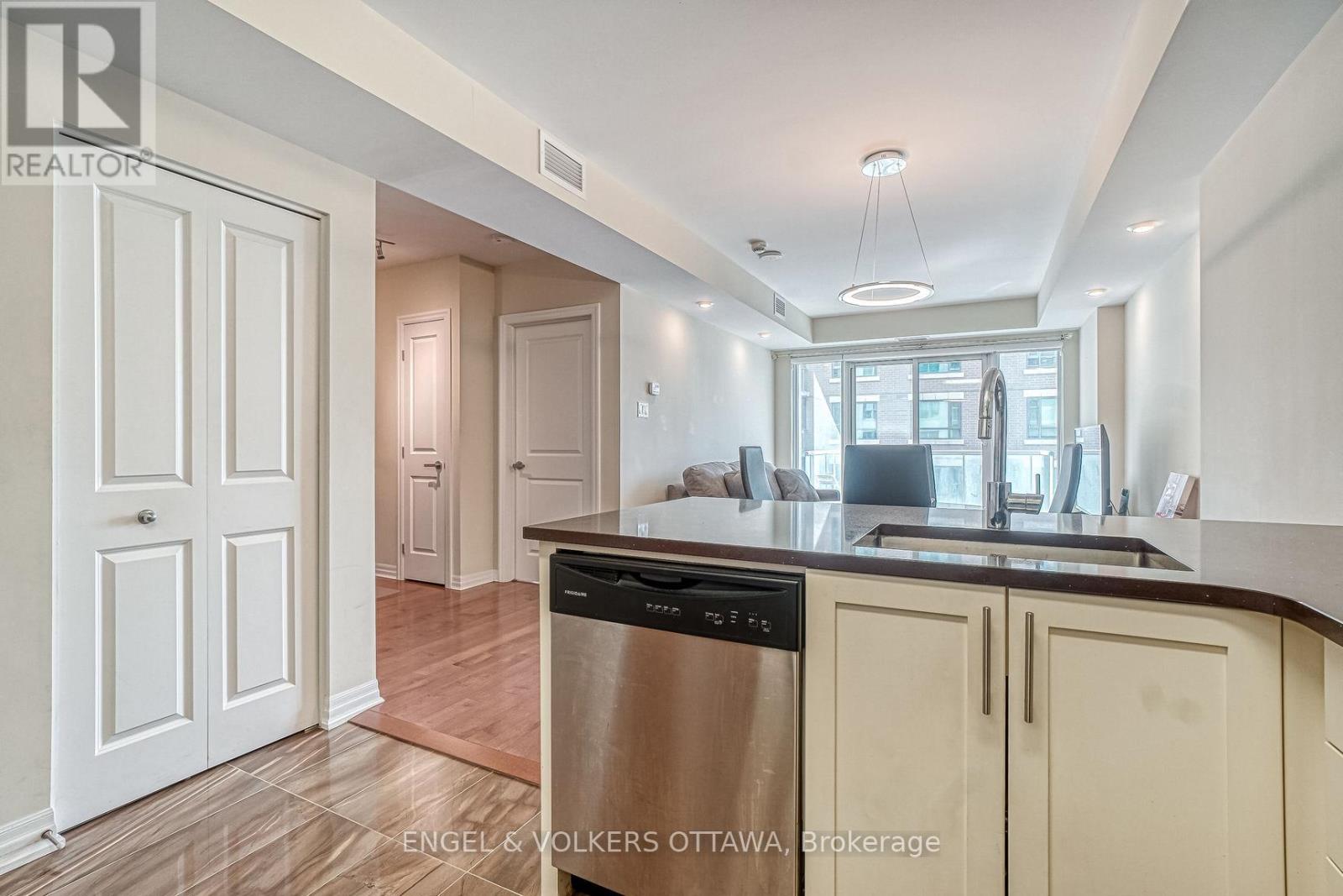 A kitchen with a stainless steel dishwasher and wooden flooring.