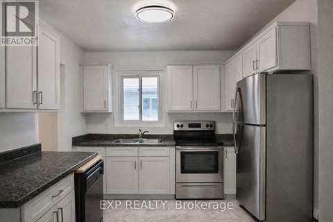 A kitchen with white cabinets and a stainless steel refrigerator.