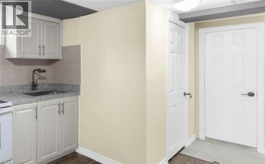A kitchen area with a sink, cabinets, and a door.