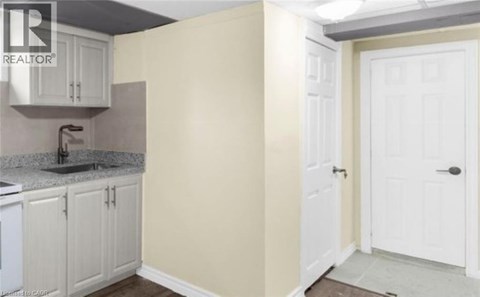 A kitchen area with a sink, cabinets, and a door.