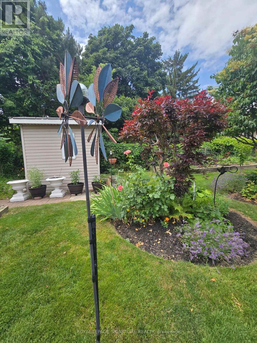 A garden with a windmill and a small building in the background.