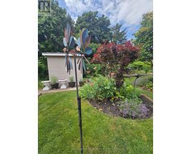 A garden with a windmill and a small building in the background.