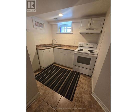 A small kitchen with a white stove and cabinets.