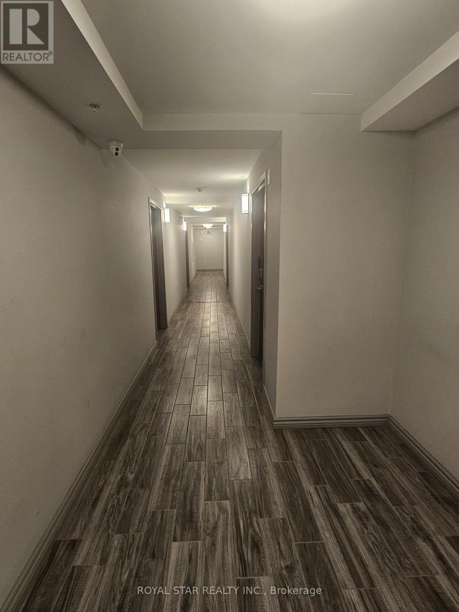A long hallway with wood flooring and white walls.