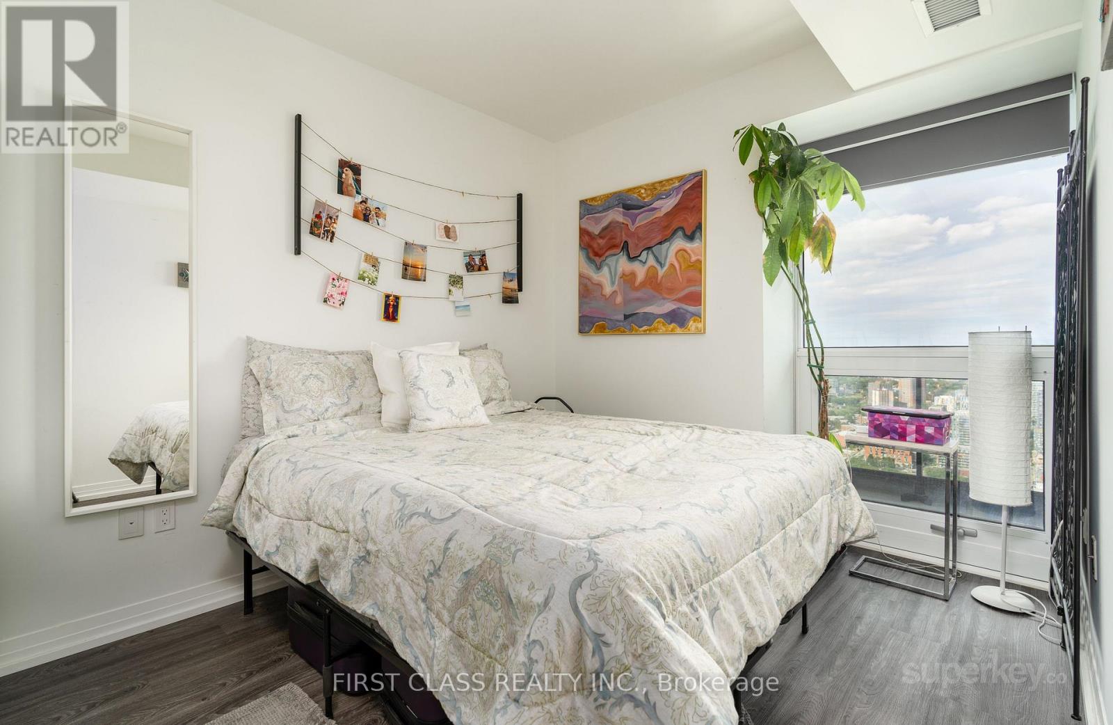 A bedroom with a large bed and a painting on the wall.