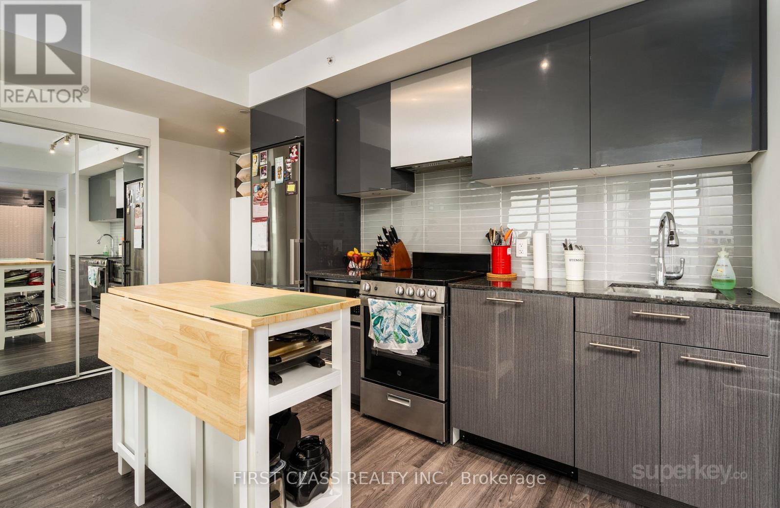 A modern kitchen with a wooden island and stainless steel appliances.