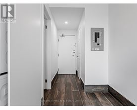 A hallway with a washer and dryer on the left and a control panel on the wall.