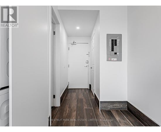 A hallway with a washer and dryer on the left and a control panel on the wall.