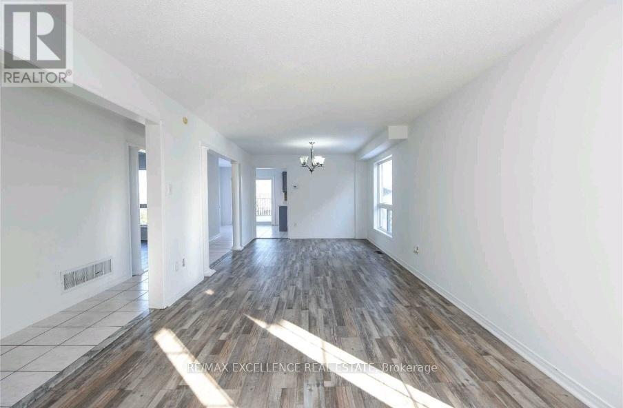 A spacious room with wood flooring and white walls.