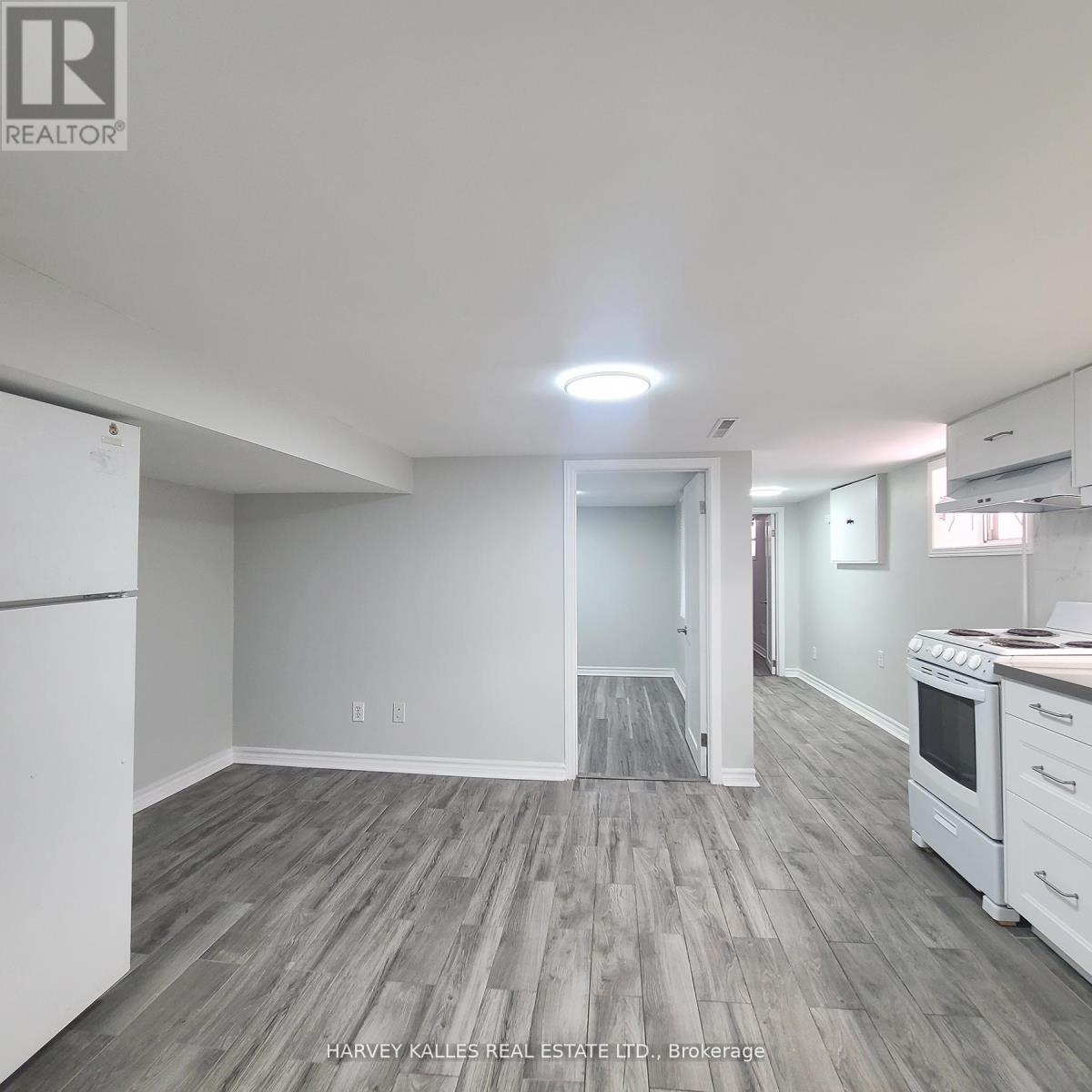 A kitchen with white appliances and wood flooring.