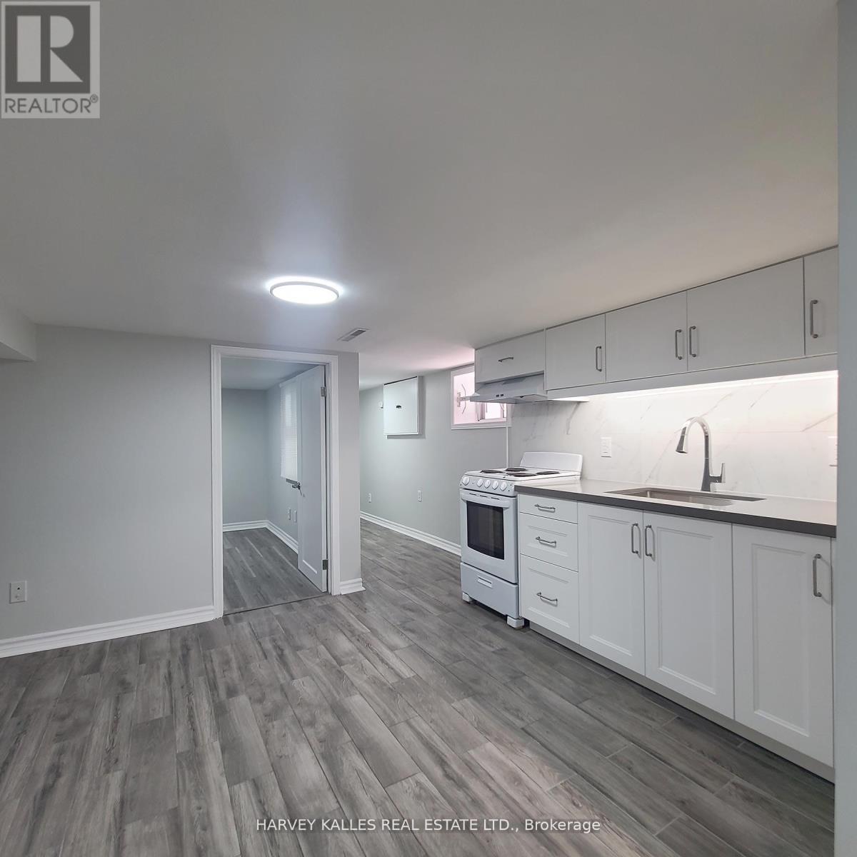 A kitchen with white cabinets and a grey floor.