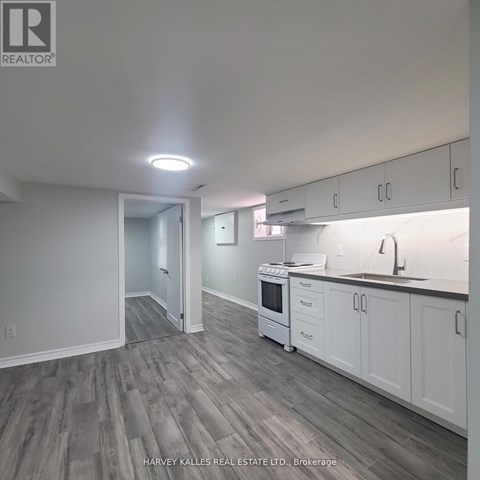 A kitchen with white cabinets and a grey floor.