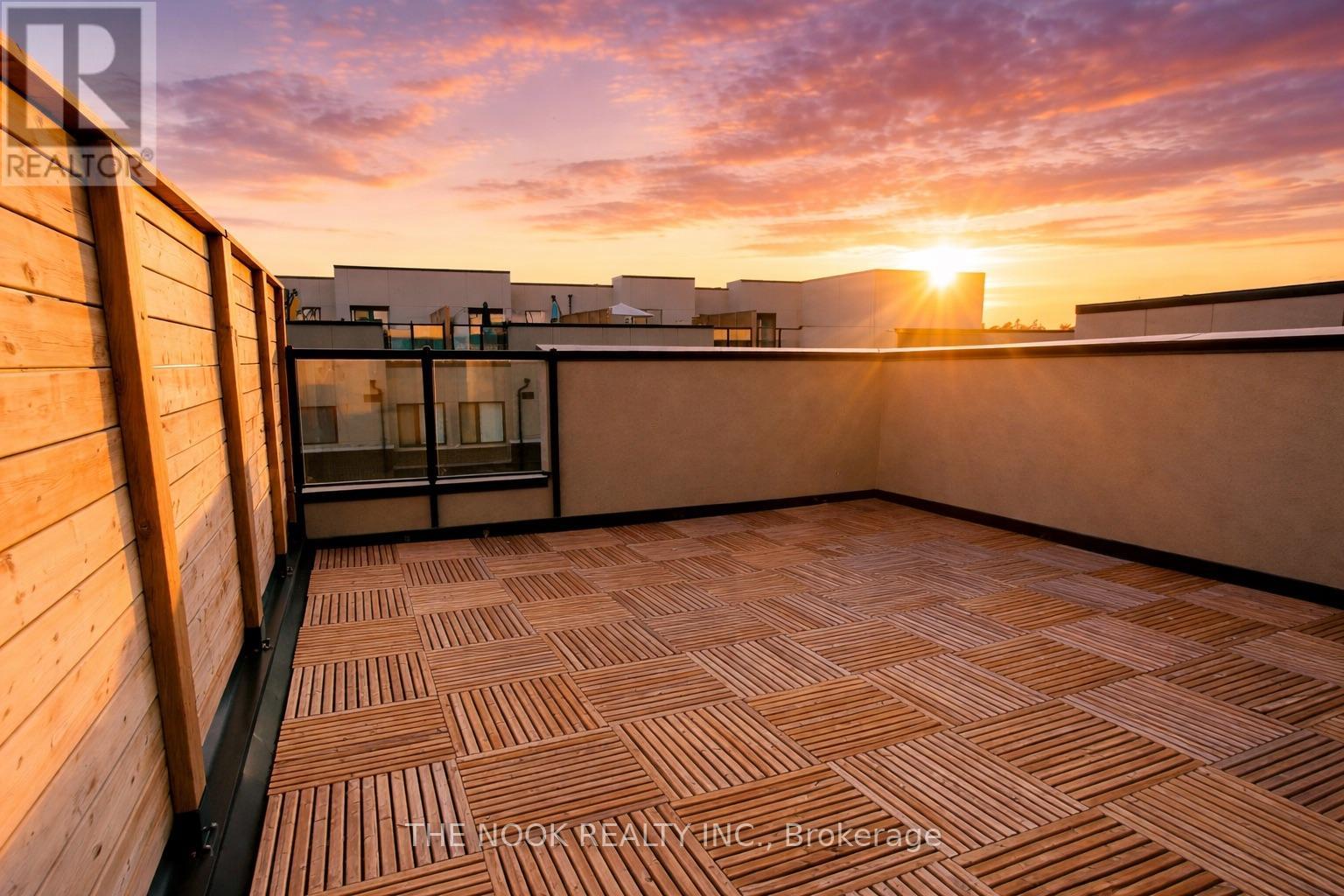 A sunset view from a rooftop terrace with wooden flooring.