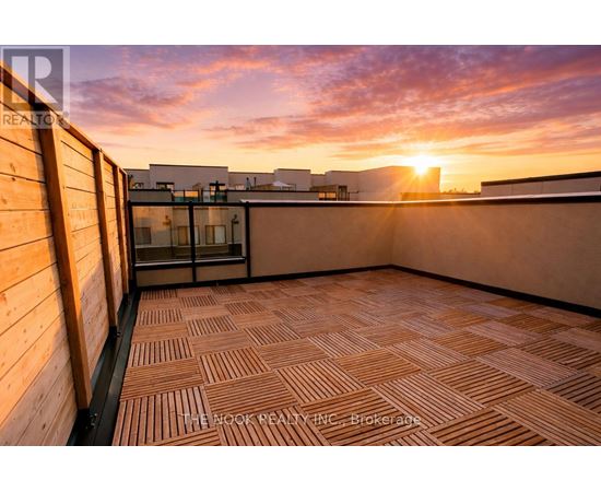 A sunset view from a rooftop terrace with wooden flooring.