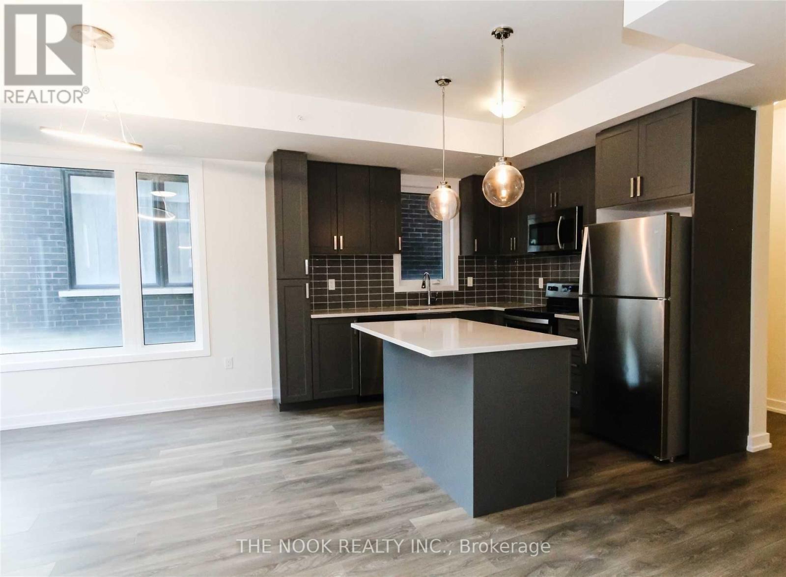 A modern kitchen with dark wood cabinets and a black refrigerator.