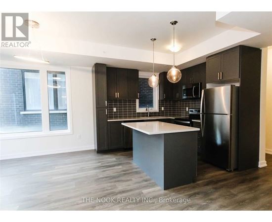 A modern kitchen with dark wood cabinets and a black refrigerator.