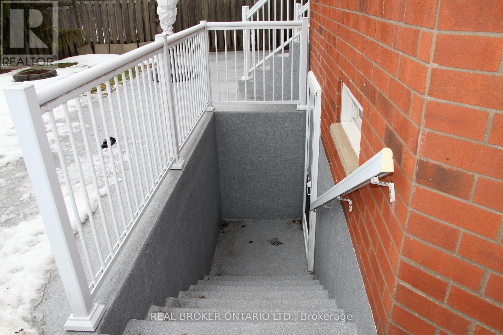 A stairway with a white railing and a brick wall.