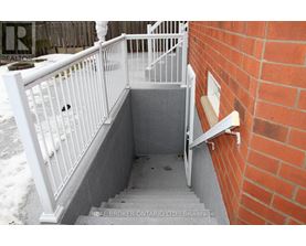 A stairway with a white railing and a brick wall.