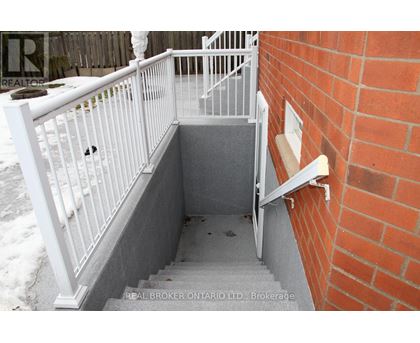 A stairway with a white railing and a brick wall.