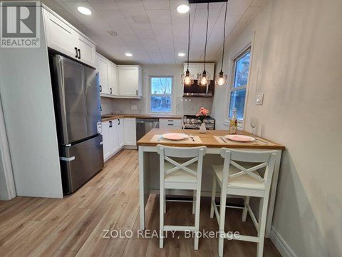 A kitchen with a table and chairs in the foreground and a refrigerator in the background.