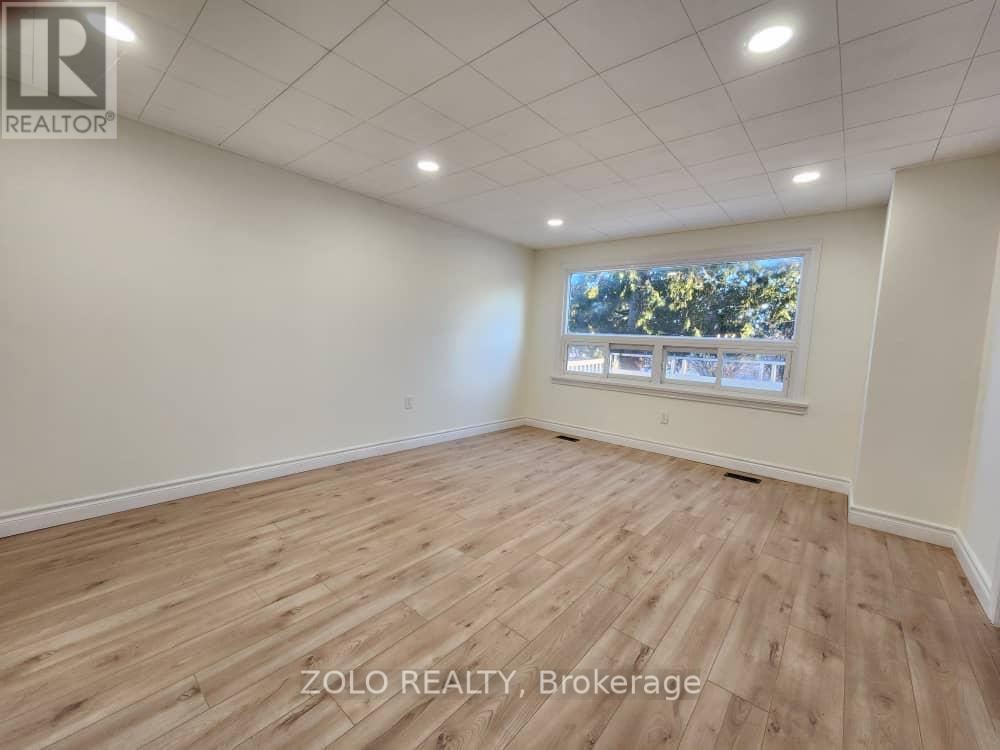 A room with wooden flooring and a window showing trees outside.