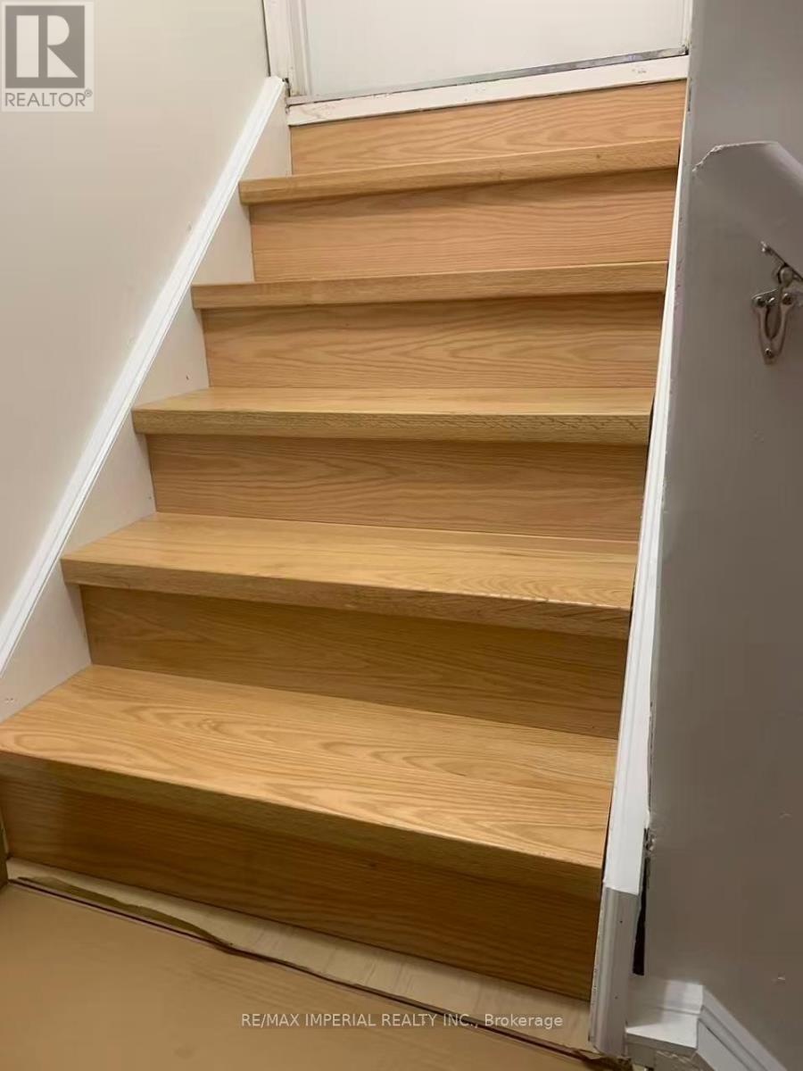 A set of wooden stairs with a white wall on the side.
