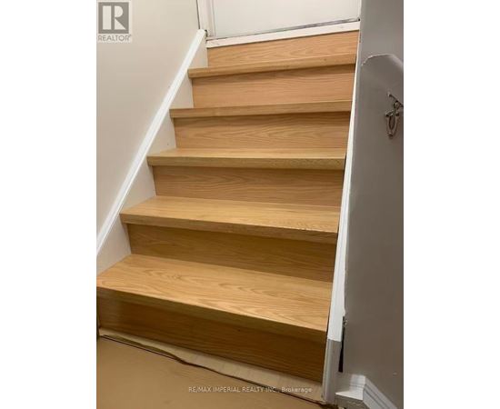 A set of wooden stairs with a white wall on the side.