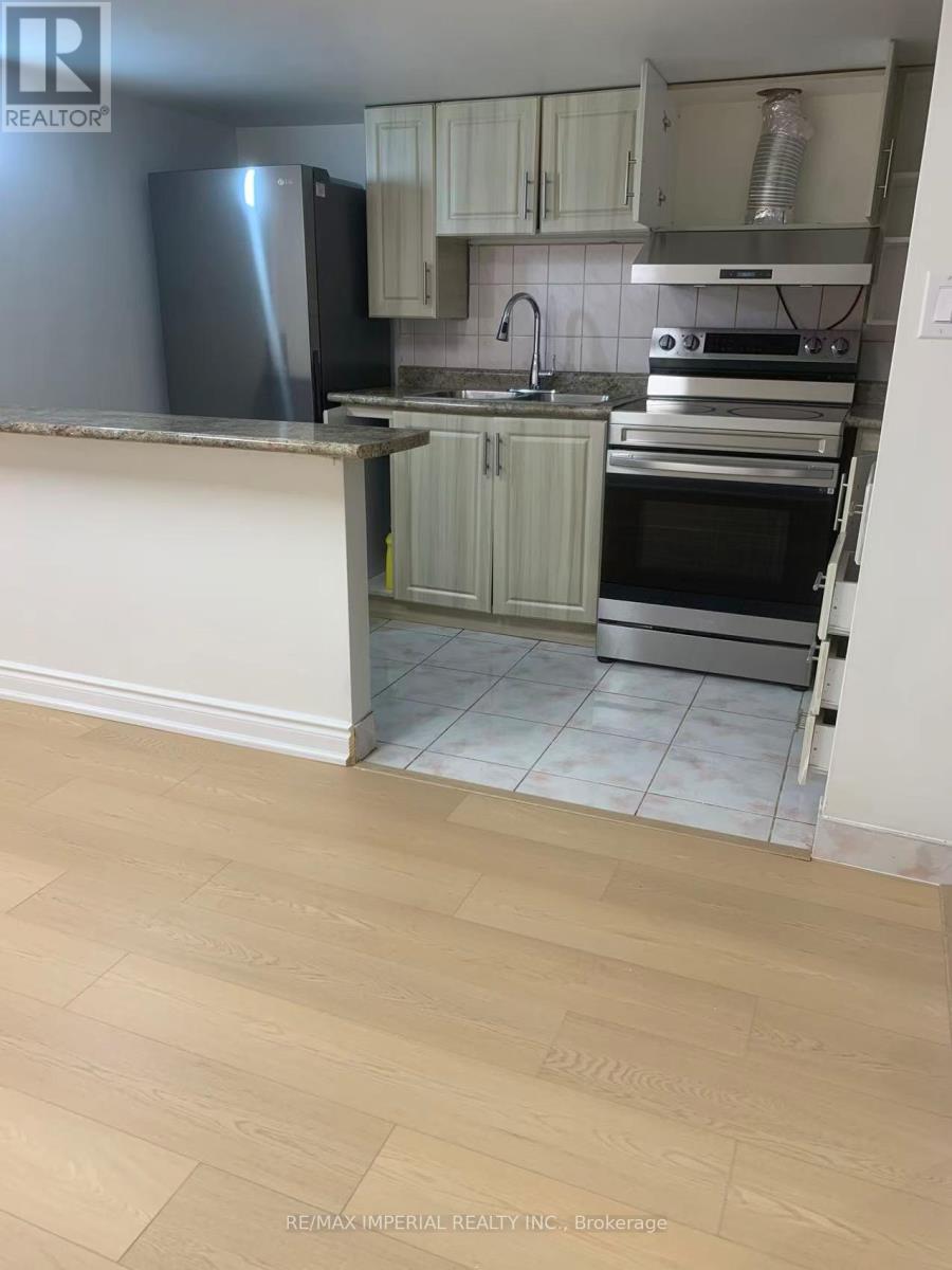 A kitchen with a refrigerator, oven, and sink.