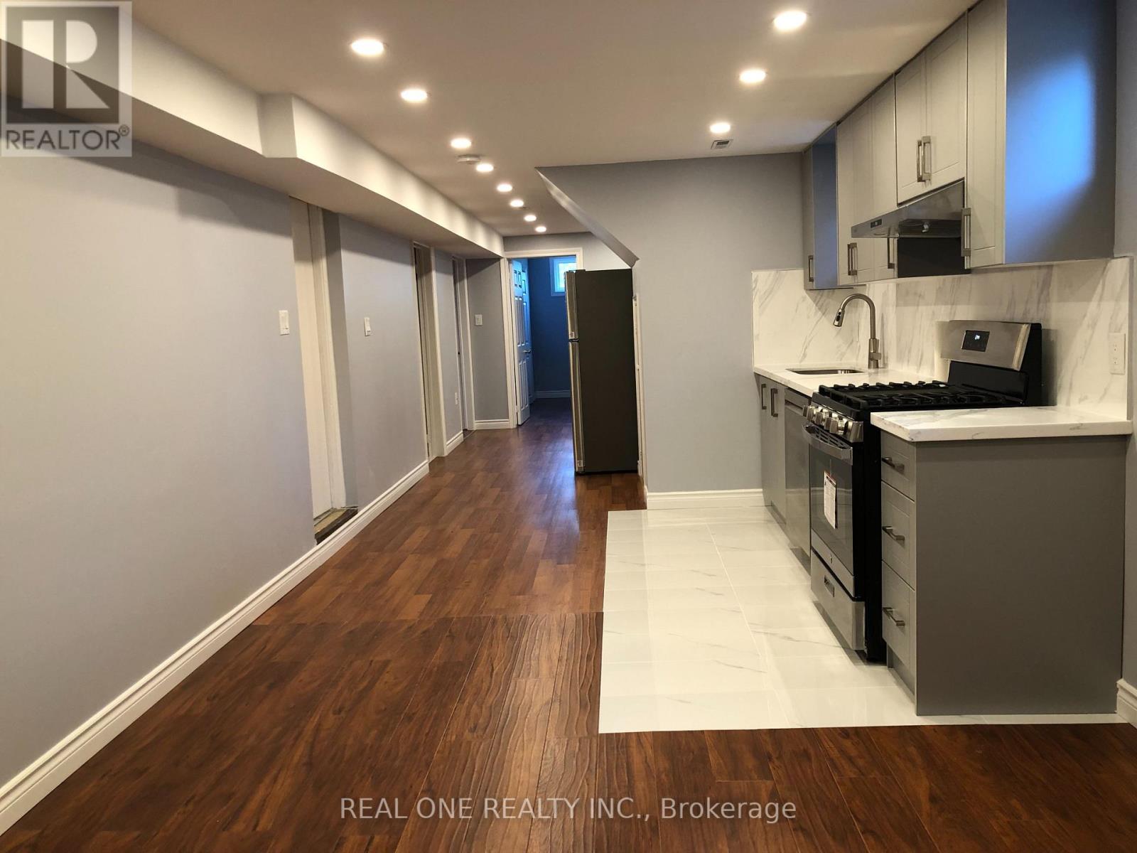 A modern kitchen with dark wood floors and white walls.