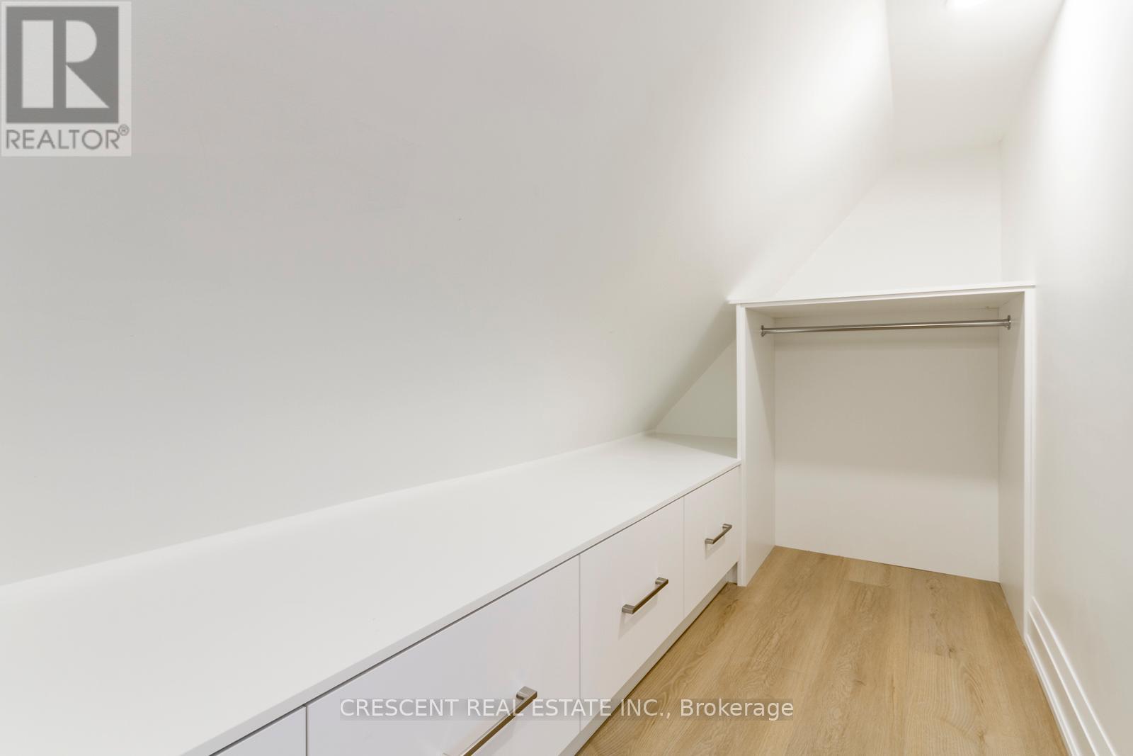 A white bedroom with a built in shelf and a wooden floor.