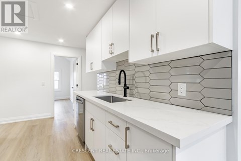 A modern kitchen with white cabinets and a marble backsplash.