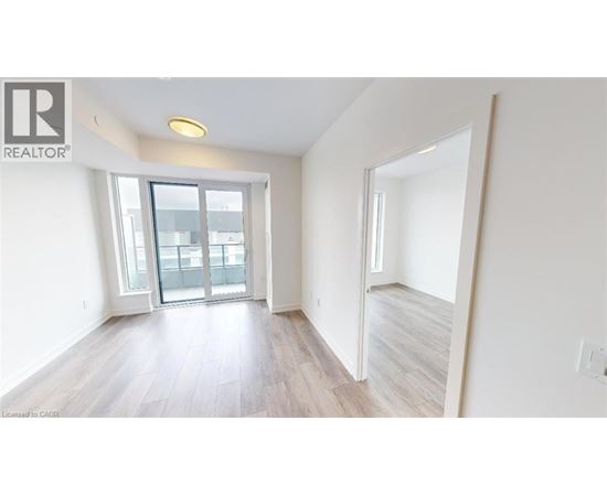 A spacious room with a sliding glass door leading to a balcony.
