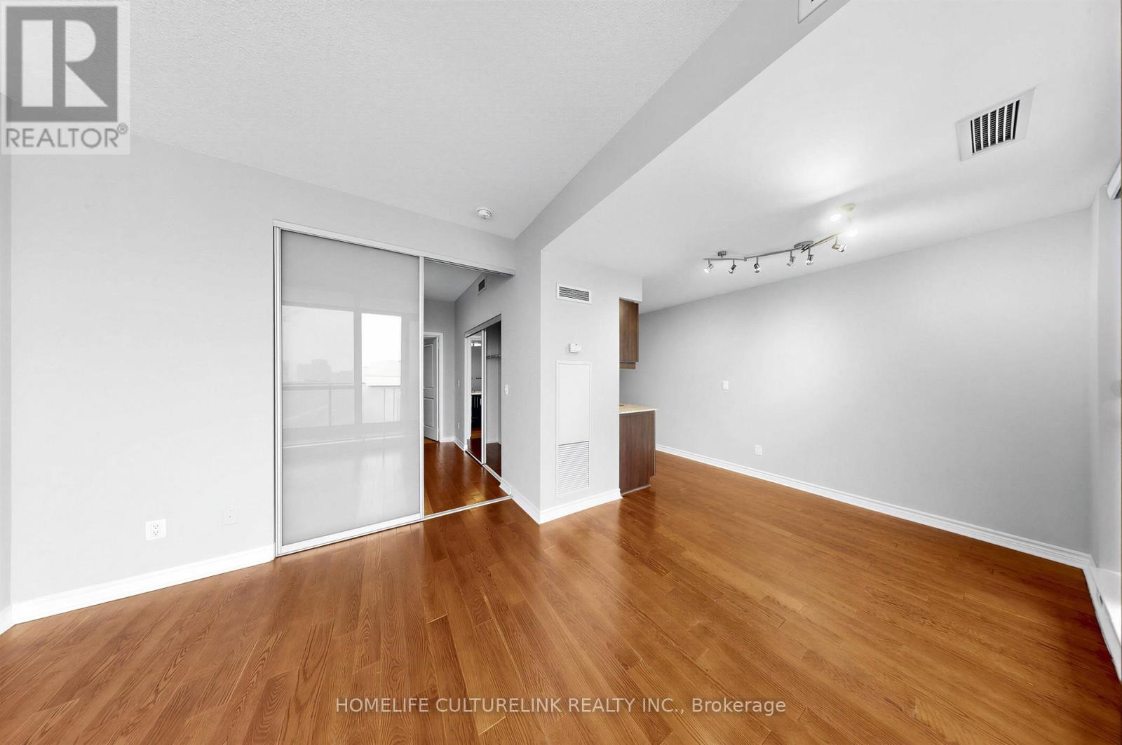 A spacious room with wooden floors and white walls.