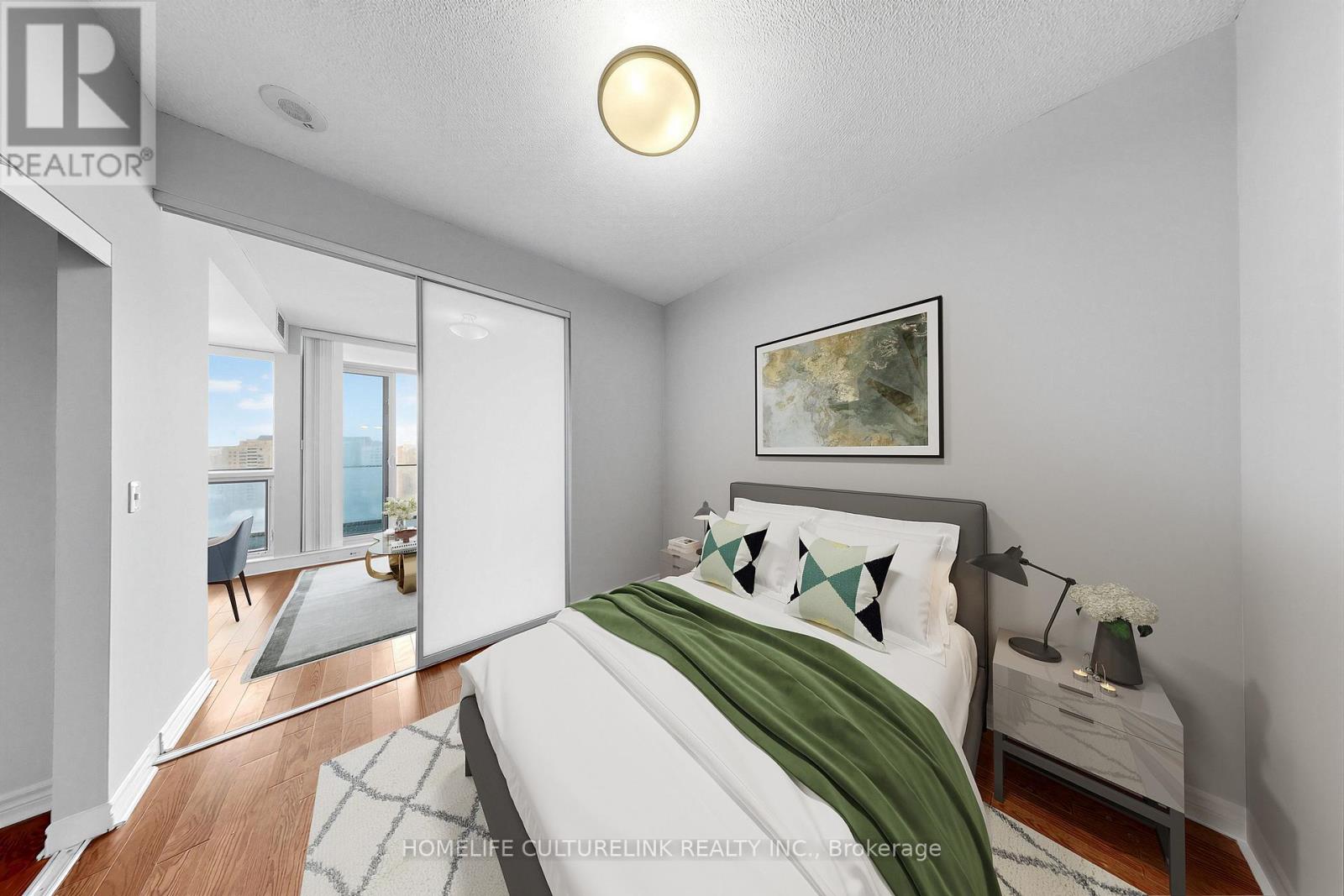 A bedroom with a bed, nightstand, and a painting on the wall.