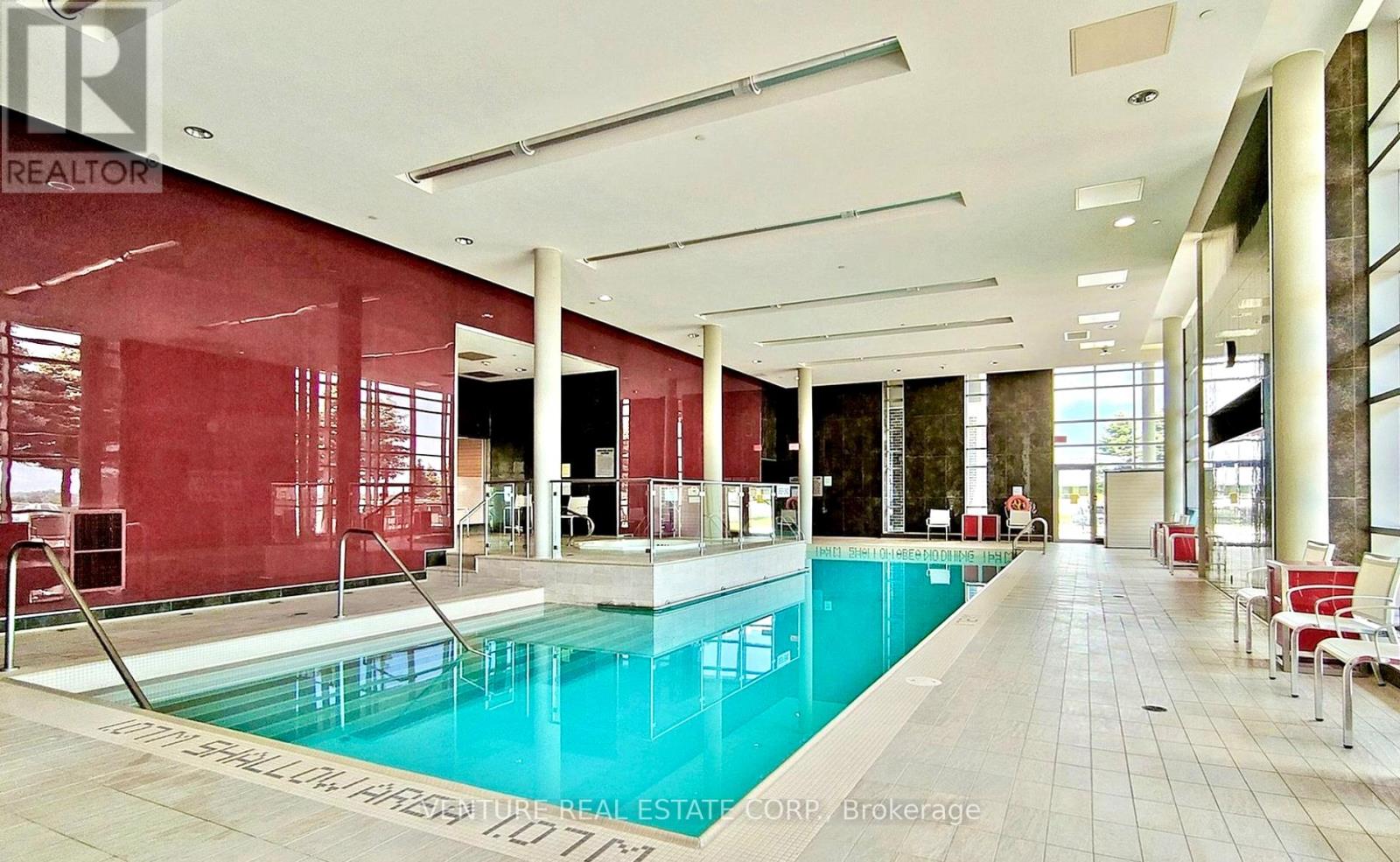 A large indoor swimming pool with a glass wall on one side.