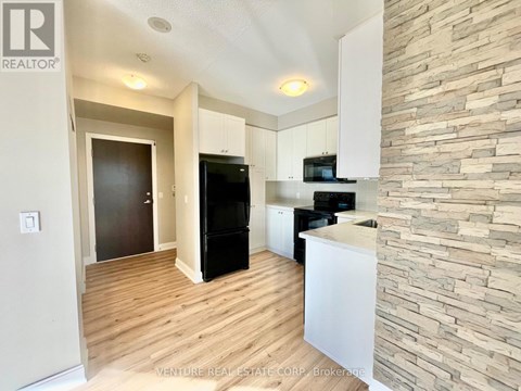 A kitchen with a black fridge and stove top oven.