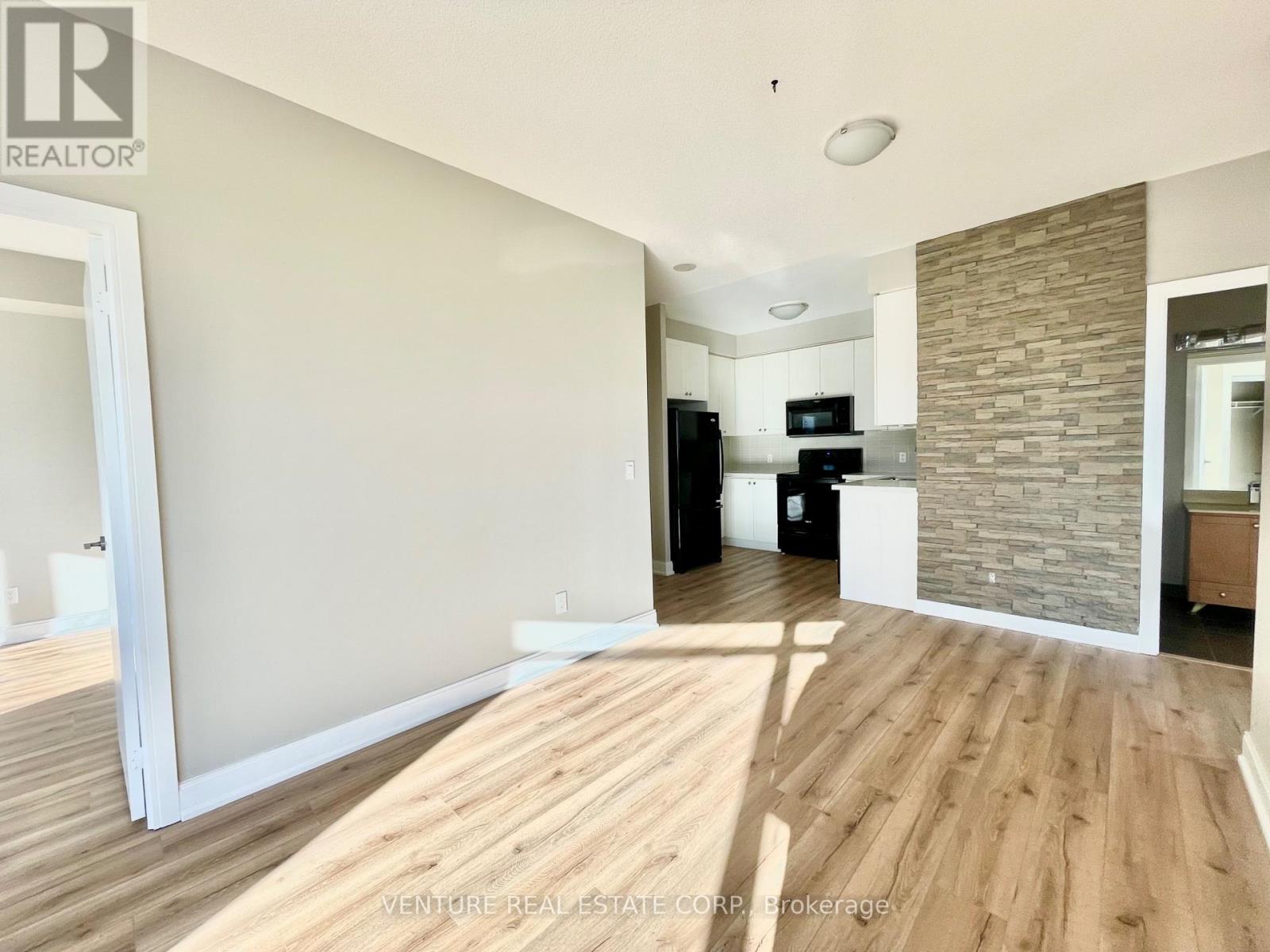 A spacious room with wooden flooring and a stone accent wall.