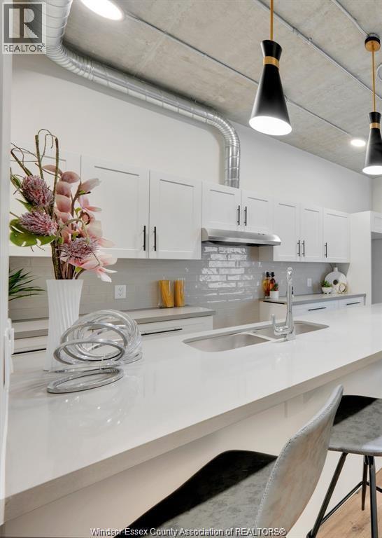 A kitchen with white countertops and a vase of flowers on the island.