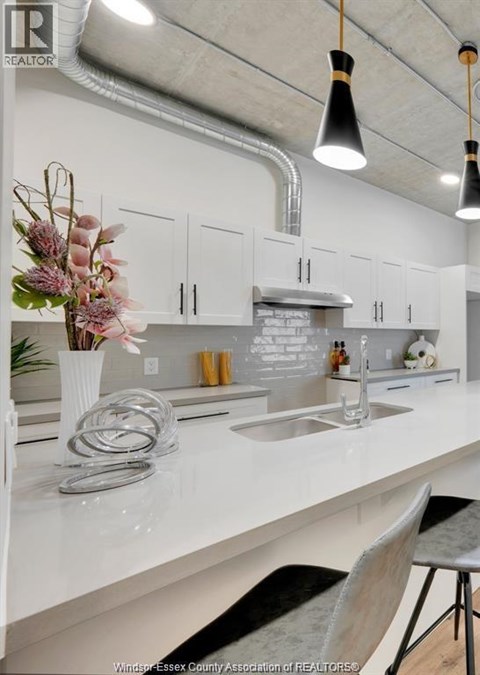 A kitchen with white countertops and a vase of flowers on the island.
