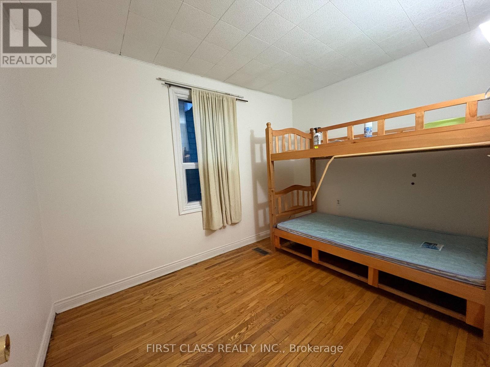 A bedroom with a bunk bed and a window with curtains.