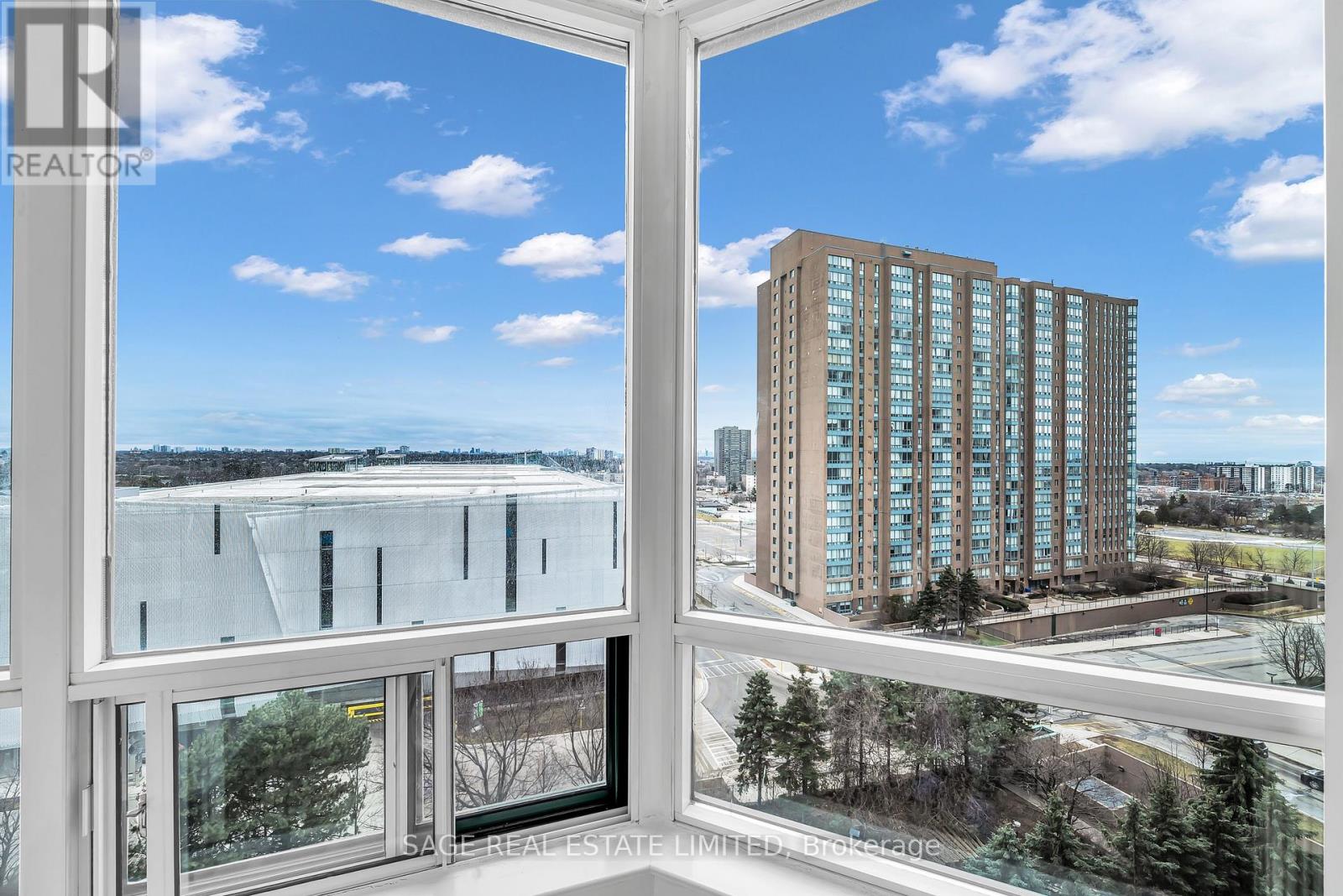 A view from a window looking out at a cityscape with a tall building in the distance.