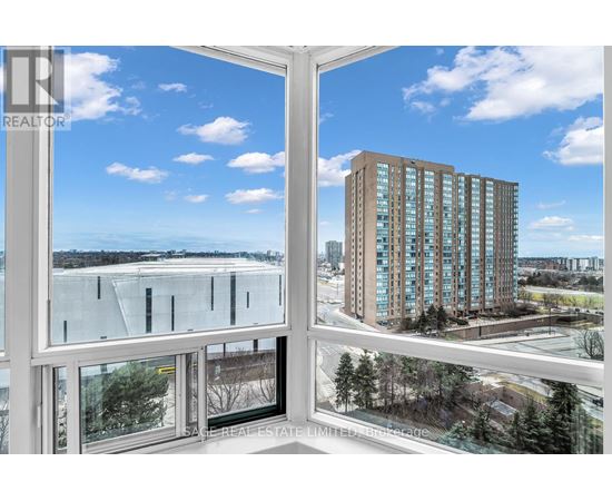 A view from a window looking out at a cityscape with a tall building in the distance.