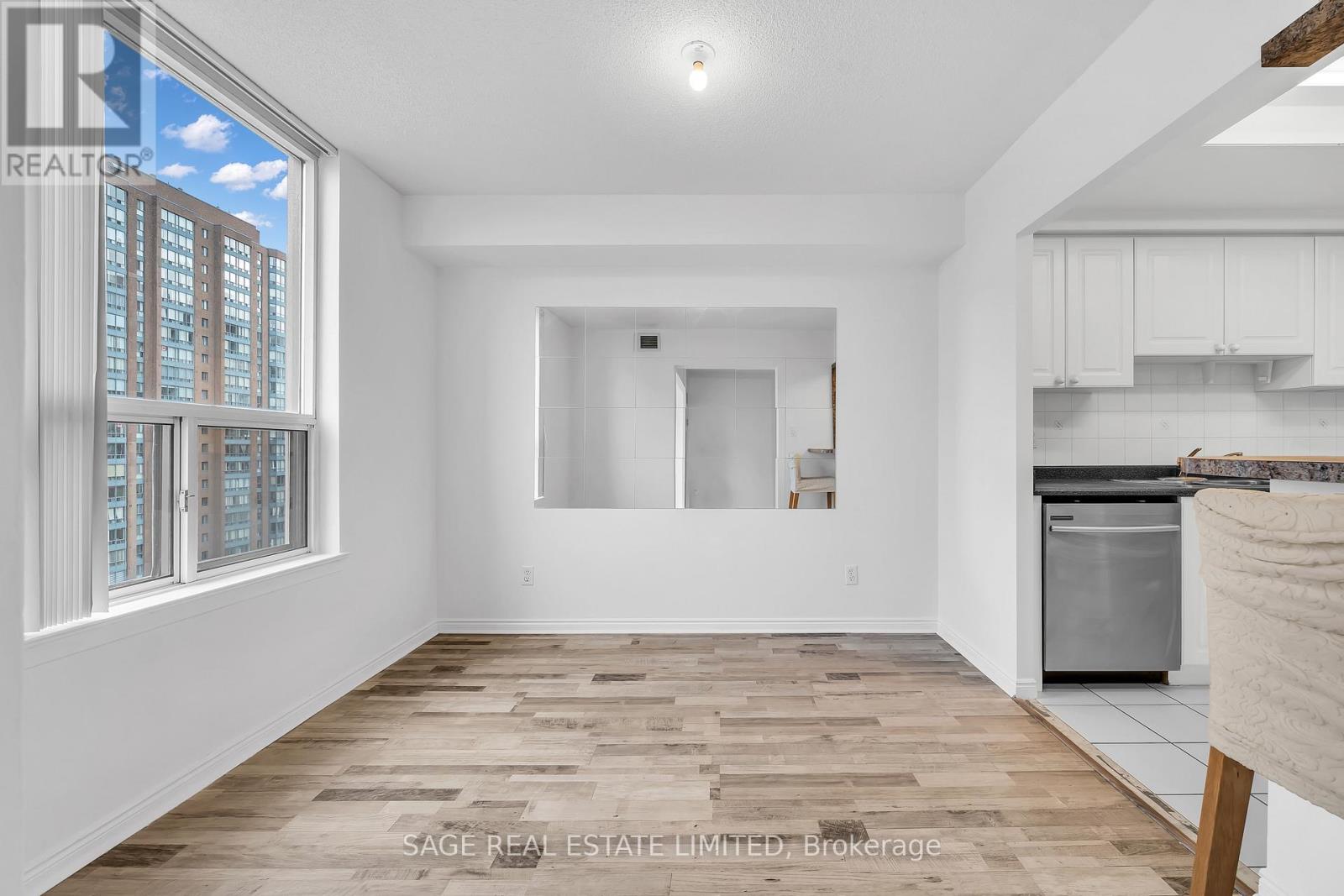 A spacious, empty room with wooden flooring and white walls.
